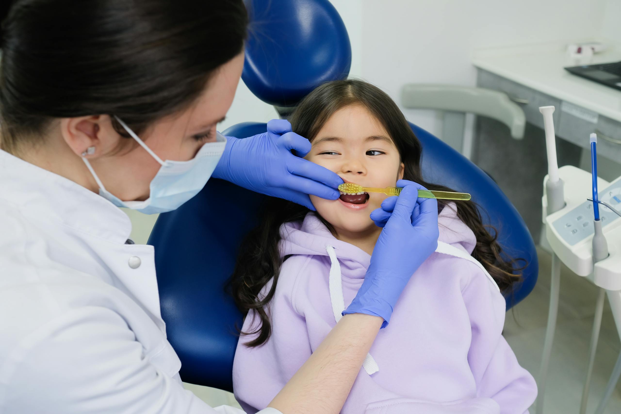 Female dentist examines a young girl's teeth in a modern dental clinic.