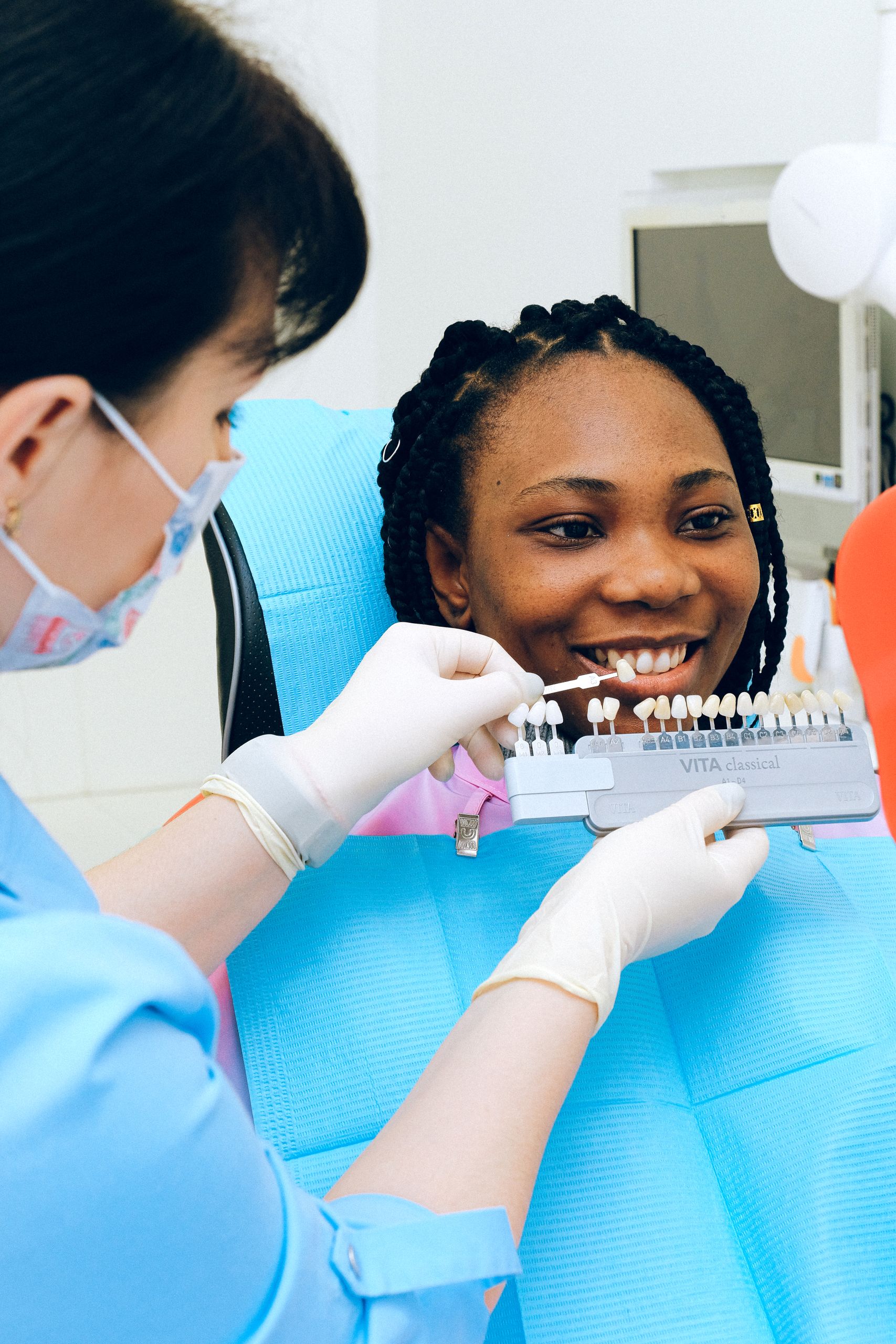 Porcelain Veneers 7 A dentist assists a smiling woman in selecting dental veneers during a check-up.