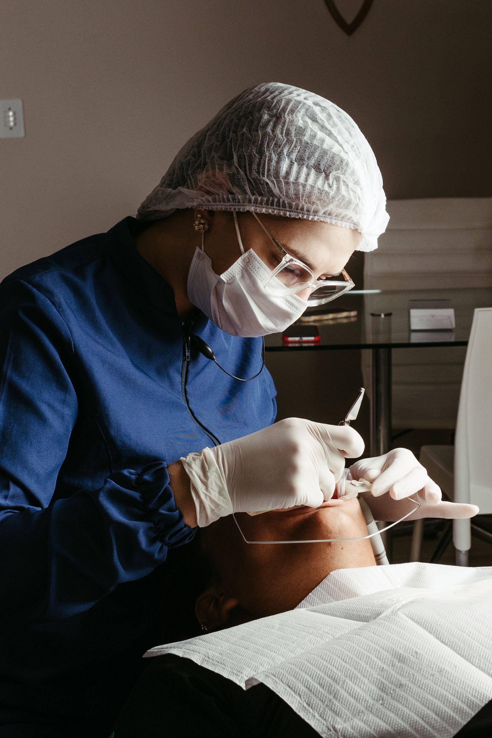 A dentist in a medical clinic performing a procedure on a patient, focusing on dental care and hygiene.