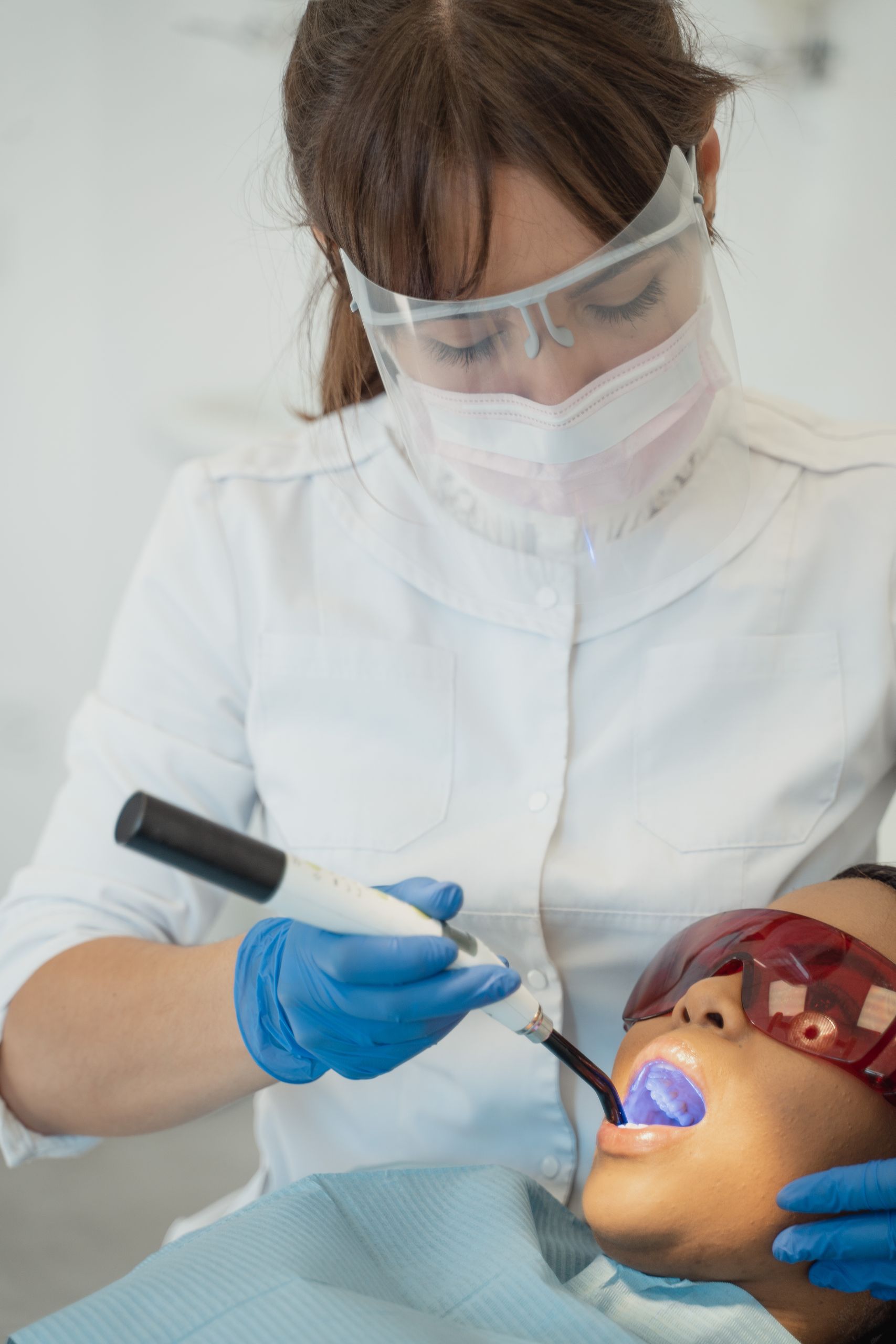 Dental Sealants 1 A dentist in protective gear performs a dental procedure on a patient in a modern clinic.