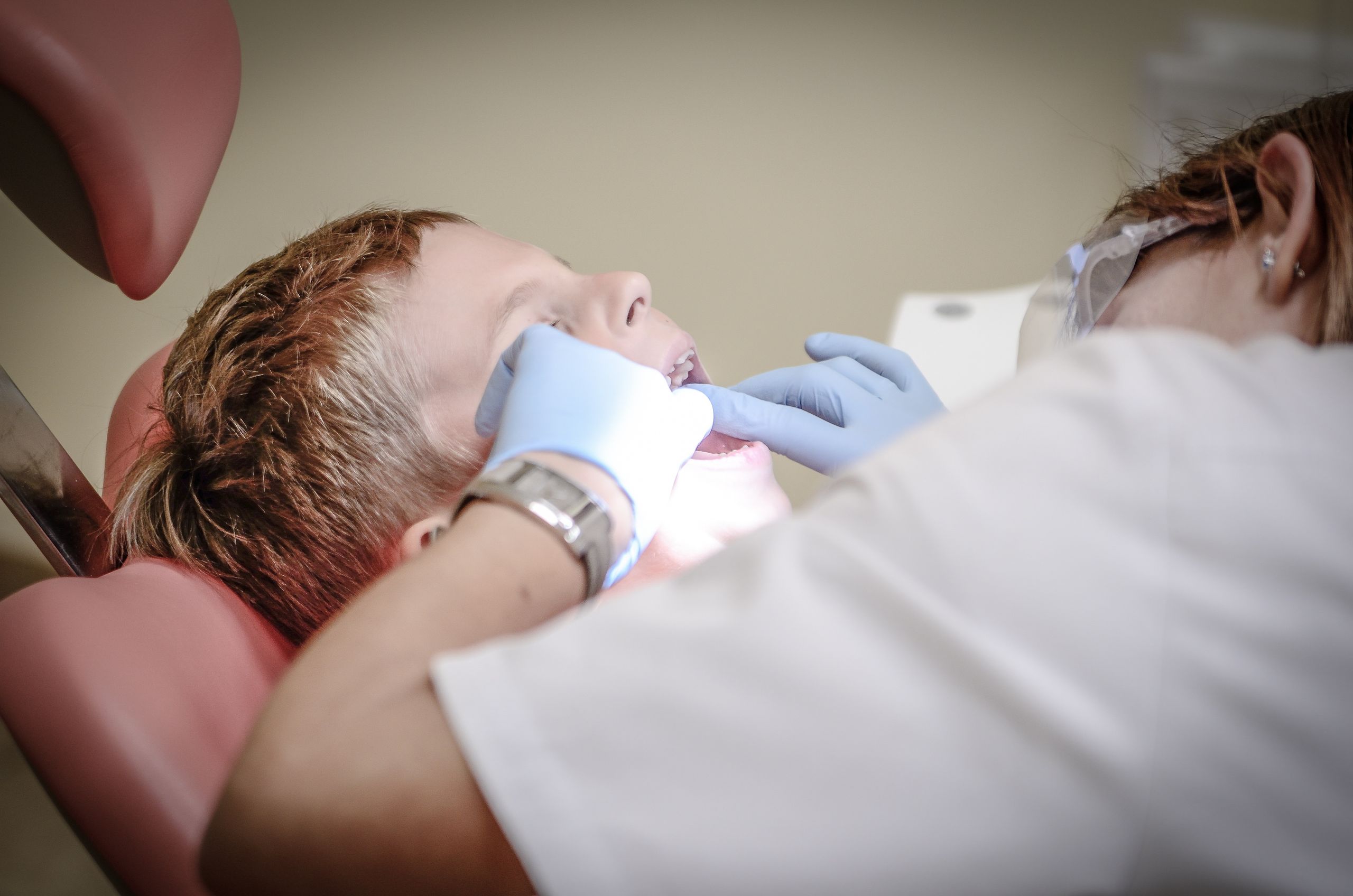 Sleep Apnea Appliances, Mouth and Sports guards 5 A young boy receiving a dental examination by a professional dentist in a clinic setting.