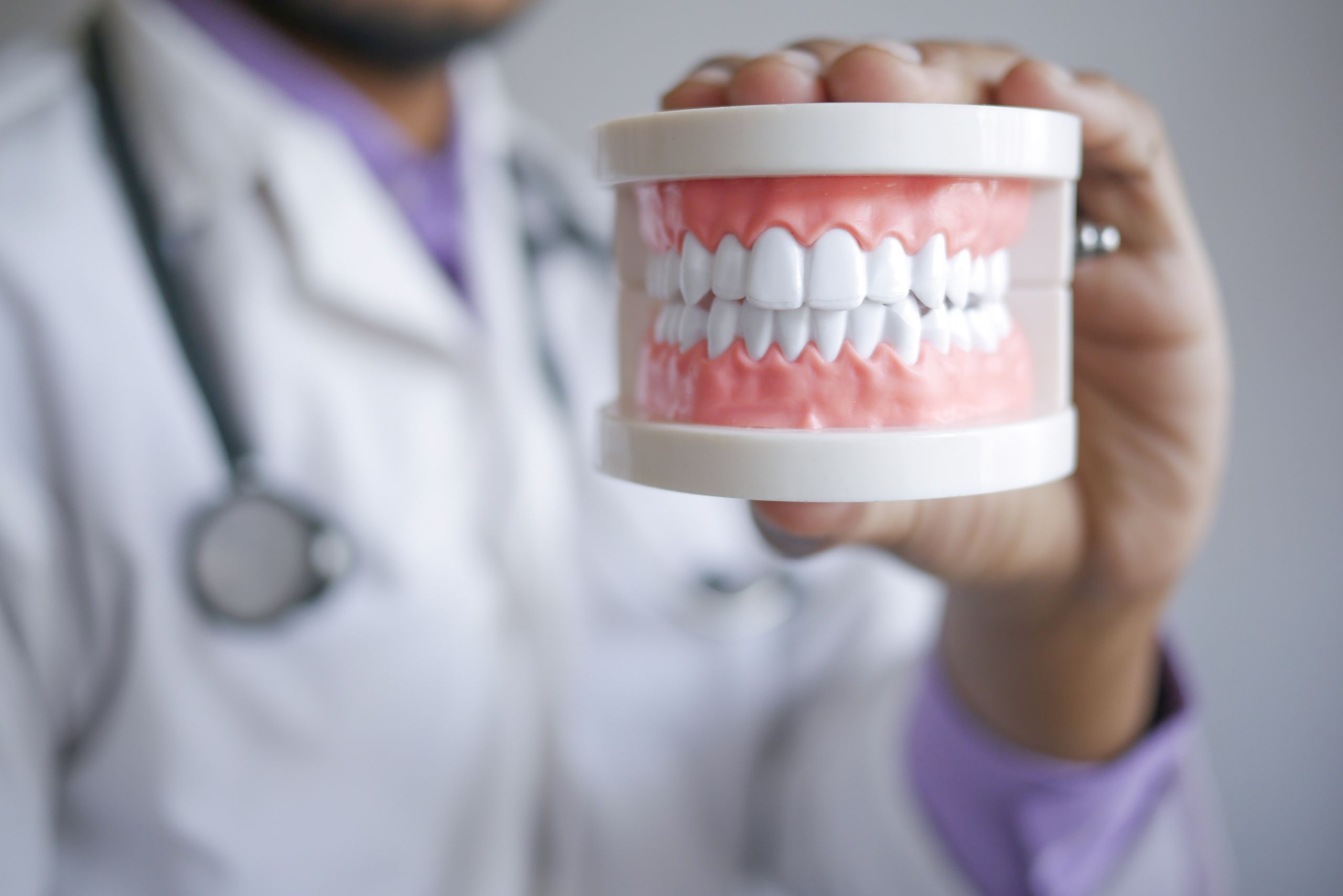 Closeup of a dentist holding a dental prosthetic in a clinical setting, emphasizing prosthodontic care.