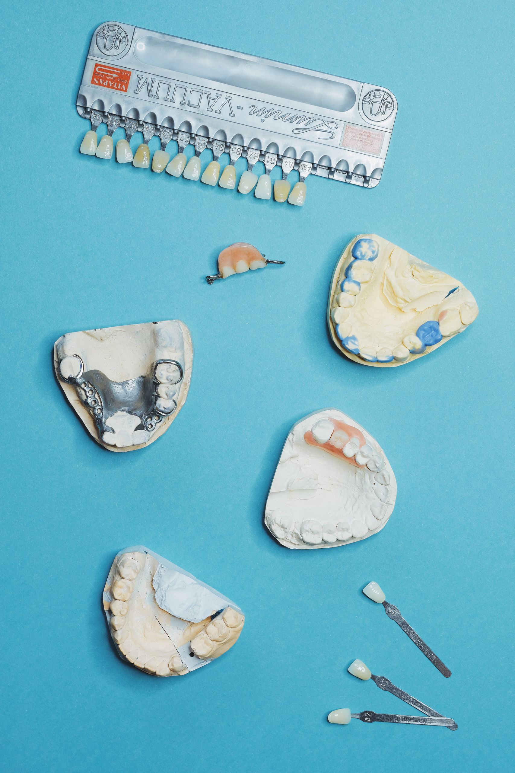 Porcelain Veneers 6 Dental molds and prosthetics on a blue surface for dental care insights.