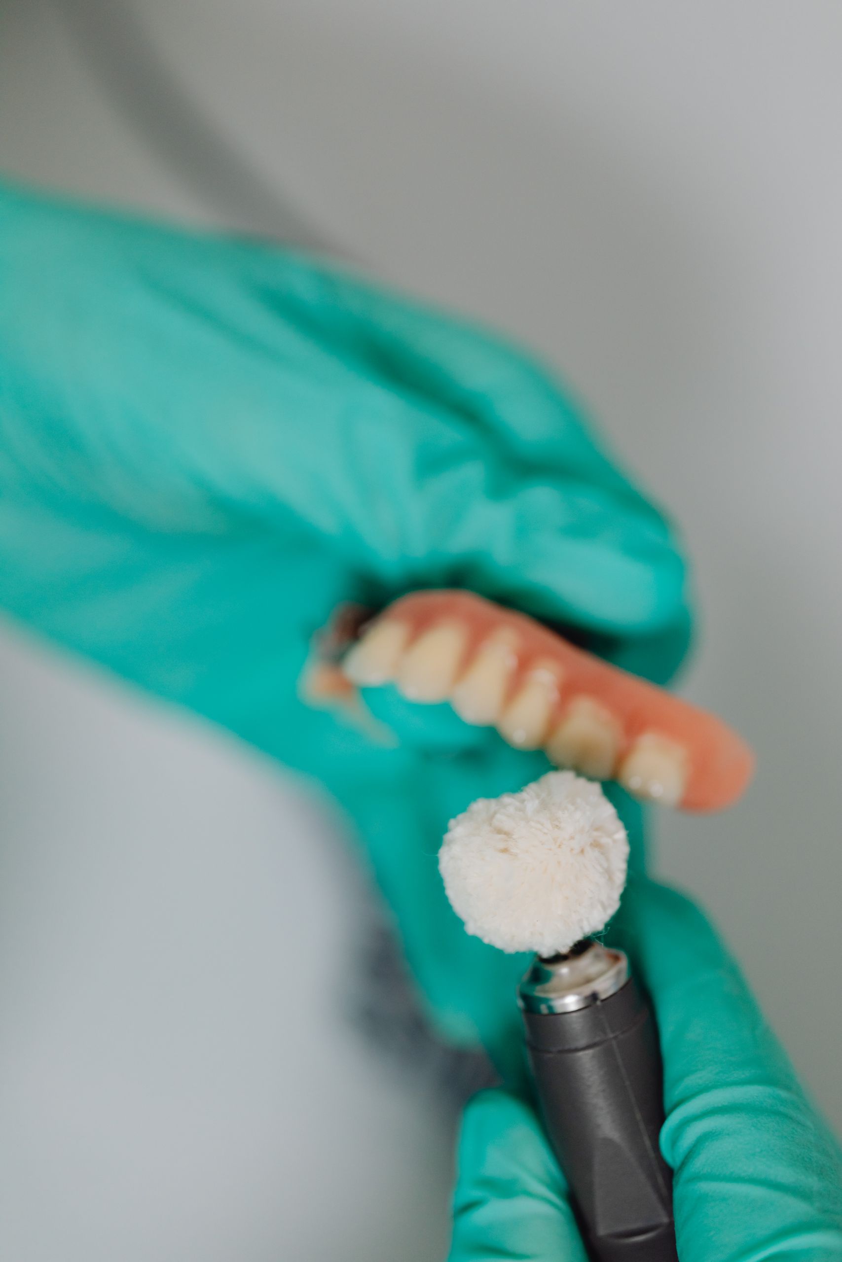 Partial and Complete Dentures 4 Detailed view of a dental polishing process with dentures and a polishing tool.