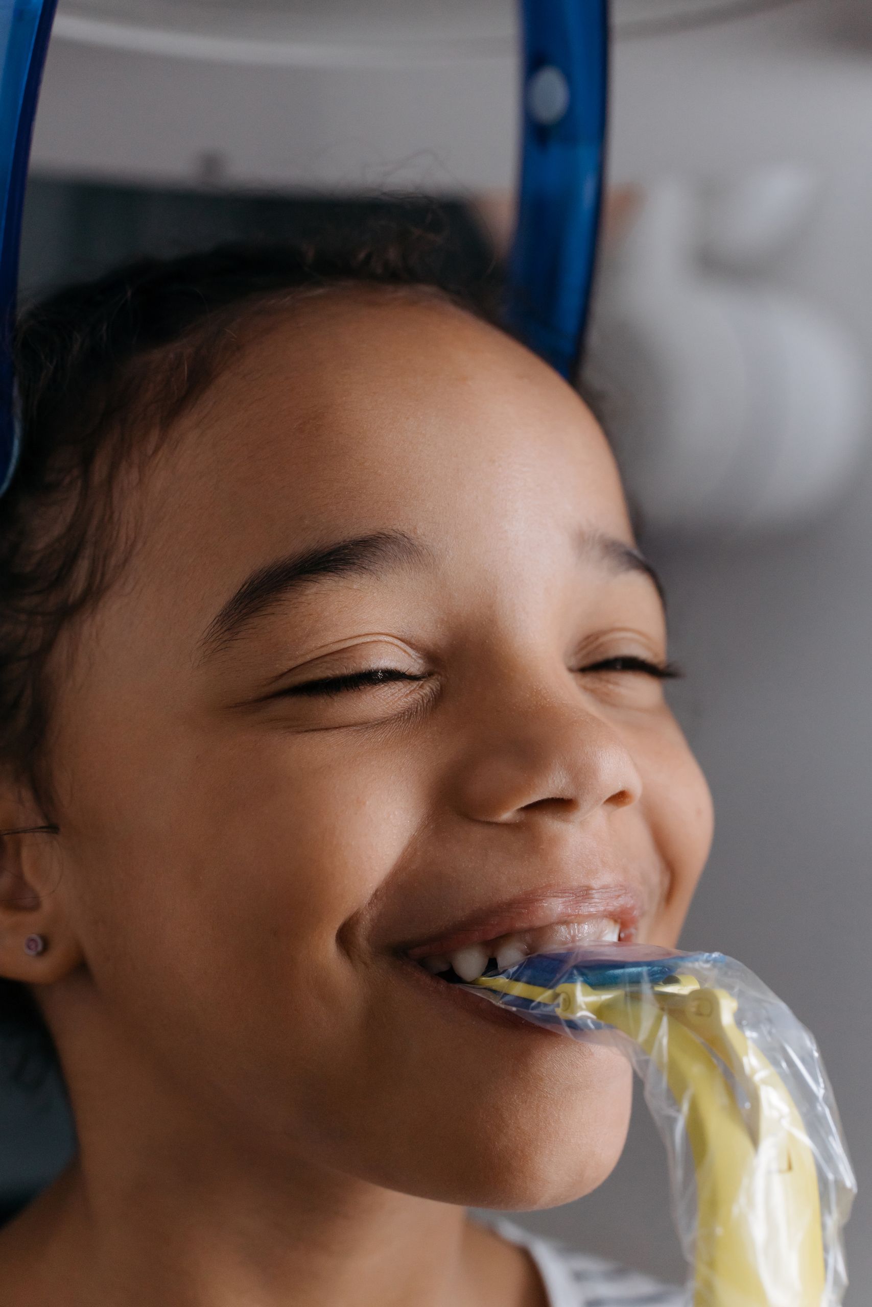 Sleep Apnea Appliances, Mouth and Sports guards 1 Smiling child undergoing dental x-ray at a clinic, emphasizing dental health and care.